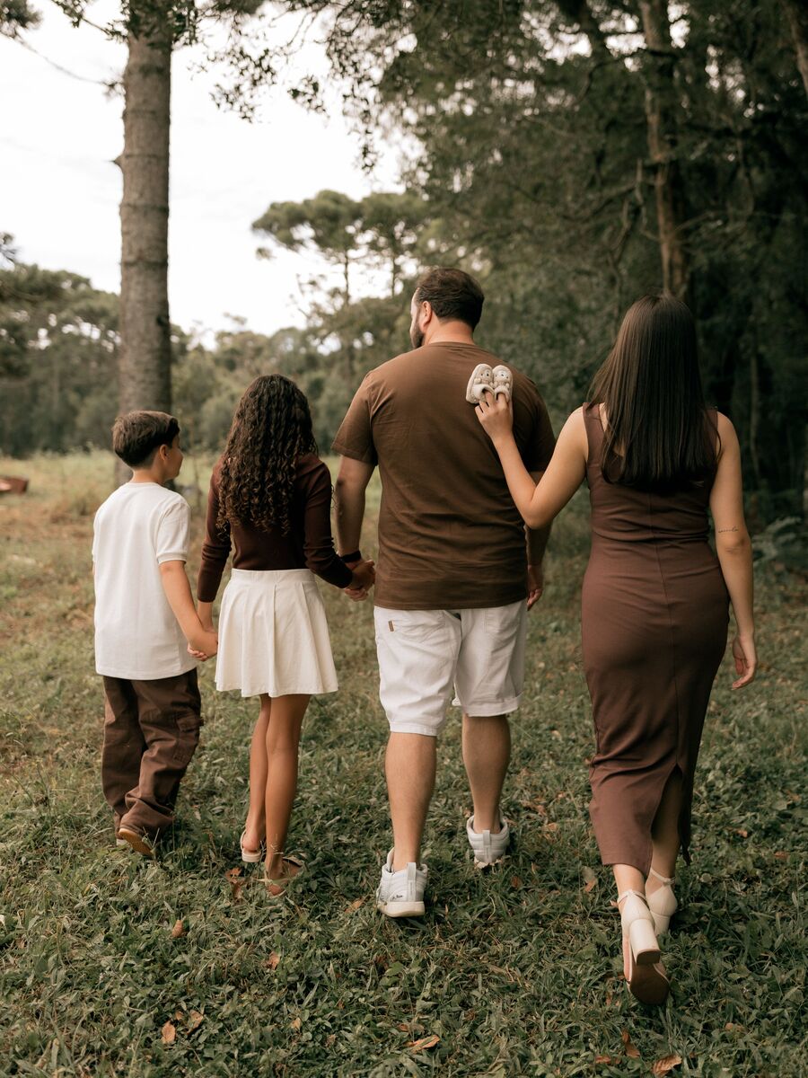 A family of four walking together along a woodland path